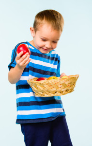 Little boy on striped t-shirt, fruit basket, studio shot and light blue background